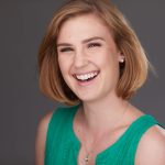 Smiling white woman with short blonde hair and a light green sleeveless shirt.