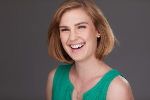 Smiling white woman with short blonde hair and a light green sleeveless shirt.